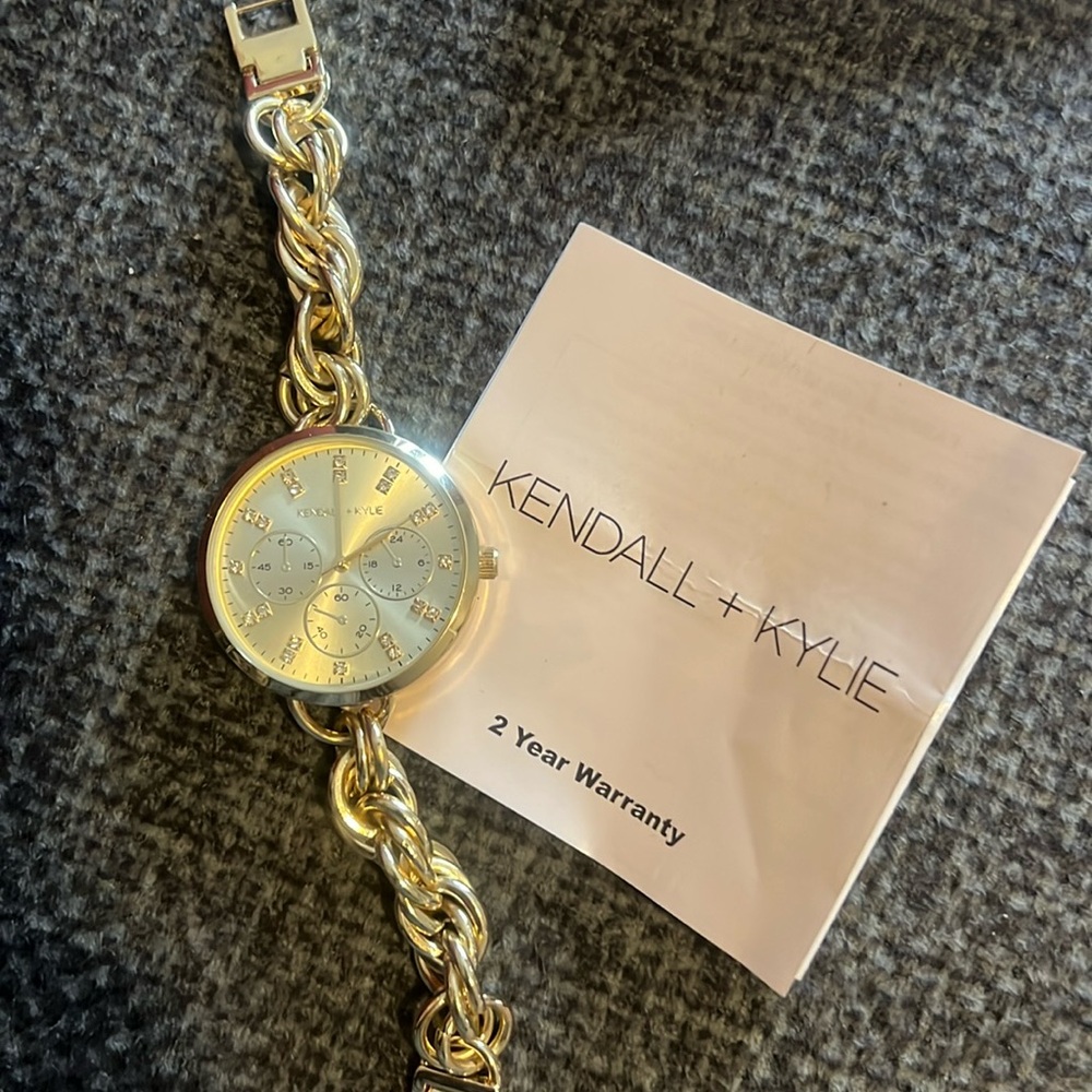Gold Kendall+Kylie bracelet watch with two year warranty.  Has a clasp closure.